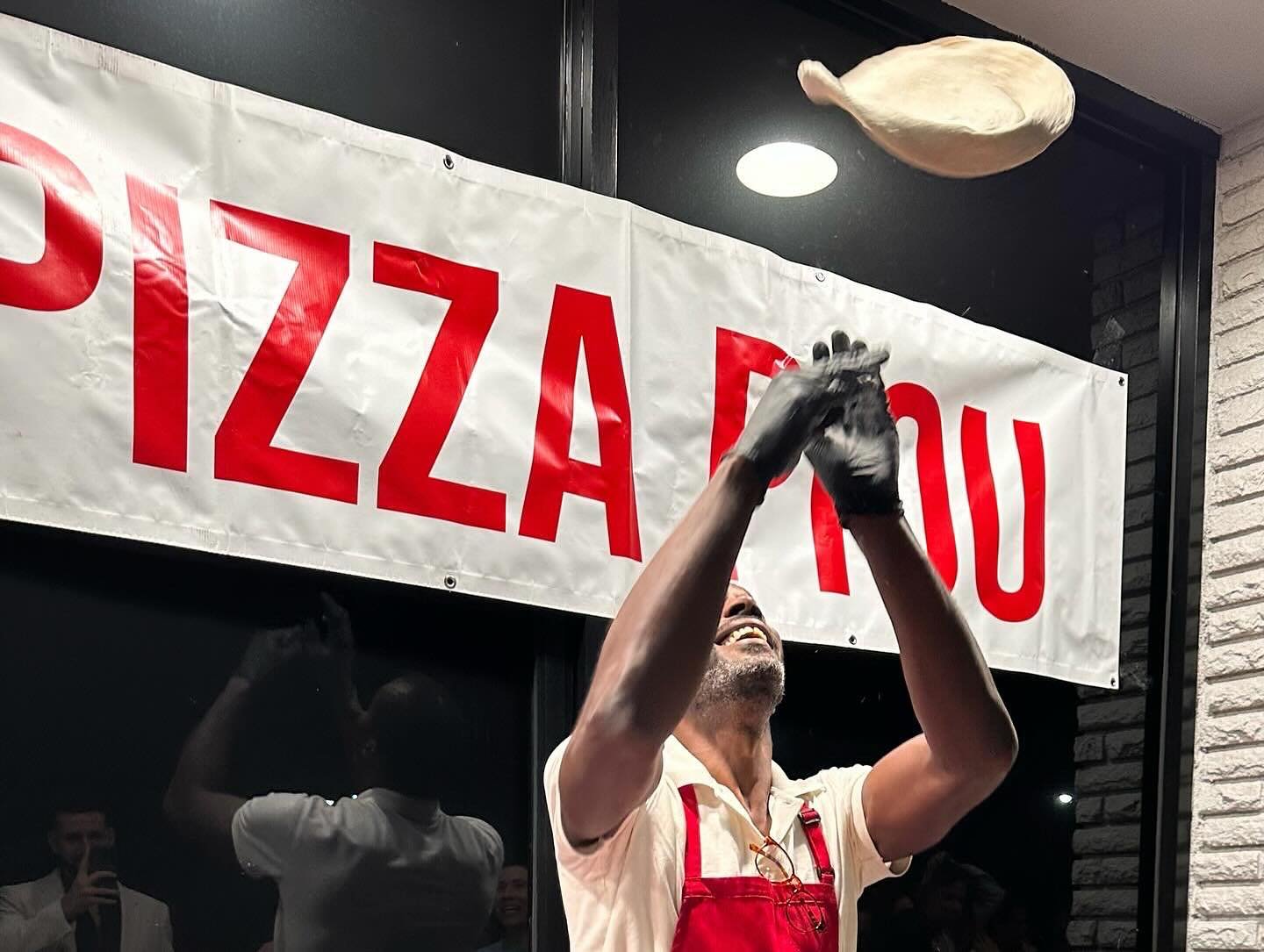 JP tossing pizza dough under the Pizza Piou banner